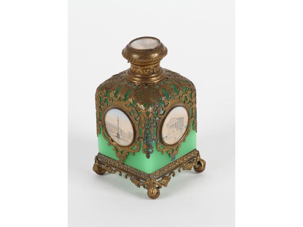 Petit flacon en opaline verte orné d'une monture en laiton et tôle (en partie oxydée) à décor de médaillons lithographiés de monuments parisien. Bon état général. Hauteur : 12 cm. (Manque le bouchon en verre)