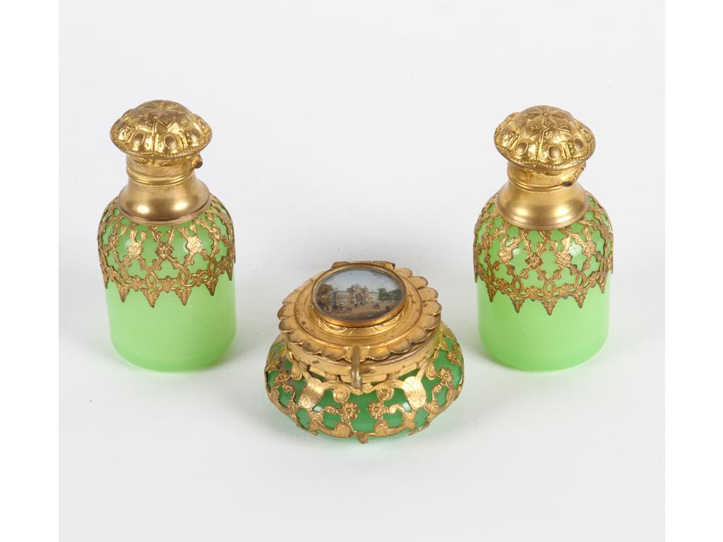 Lot en opaline verte et monture en laiton et tôle dorée comprenant : deux petits flacons. Hauteur : 7 cm. Et une petite boîte à pilules ornée sur le couvercle d'une lithographie. (Bon état général, fêle sur le verre du couvercle de la boîte).