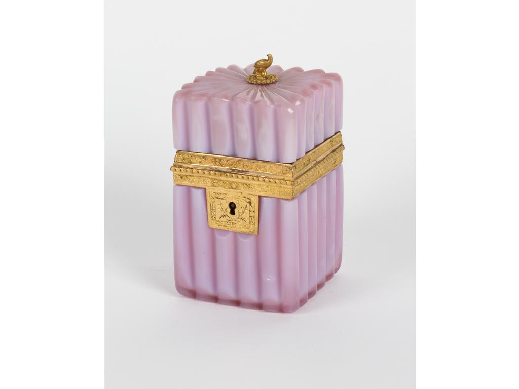 Petit coffret en opaline rose hortensia cannelé. Monture en laiton et petit fretel à décor d'oiseau (recollé). (Sans sa clé et quelques défauts sur les cannelures). Dim :  11 x 7 x 7 cm.