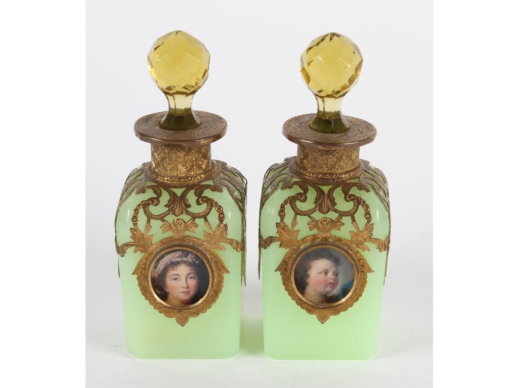 Paire de flacons en opaline verte sur une monture en laiton et tôle dorée, ornés chacun d'une image en médaillon (ange et portrait). Bon état, bouchons en verre jaune taillé non d'origine, rapportés. Hauteur : 14 cm.