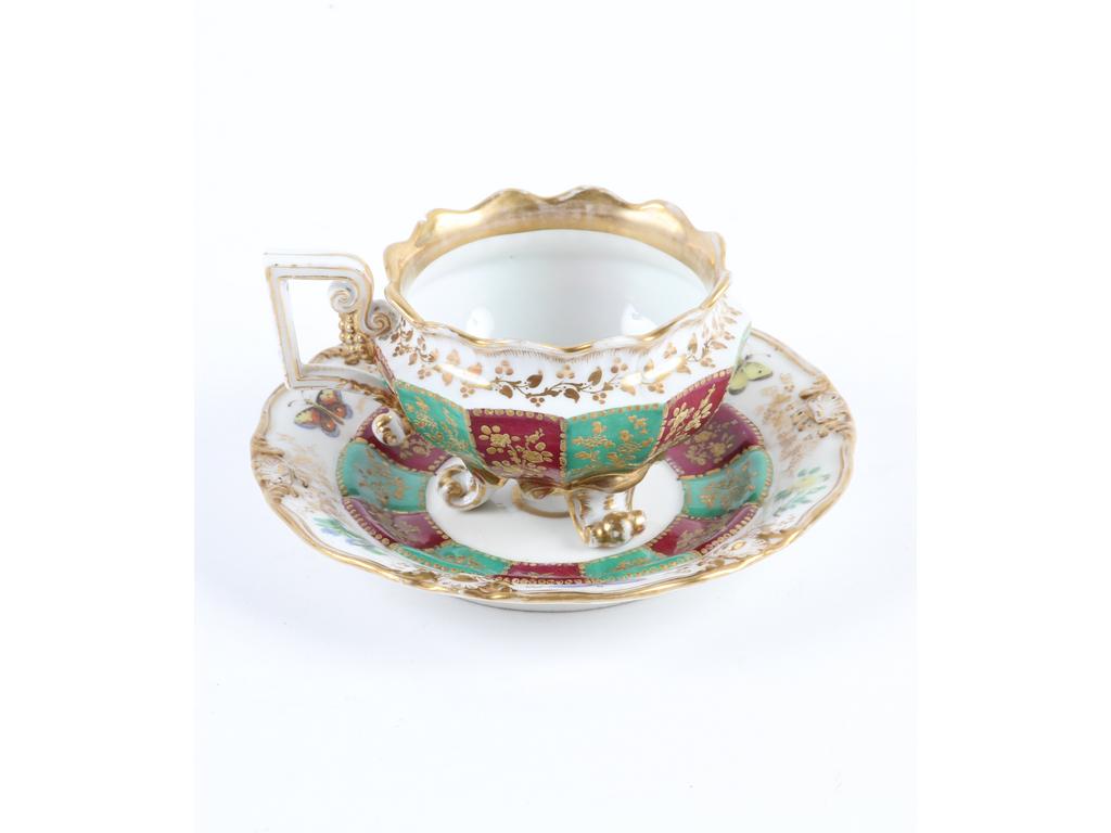 PARIS, Jacob PETIT : Tasse et sous-tasse en porcelaine à riche décor peint de fleurs et papillons. Marquée JP. (Un éclat sous la tasse).