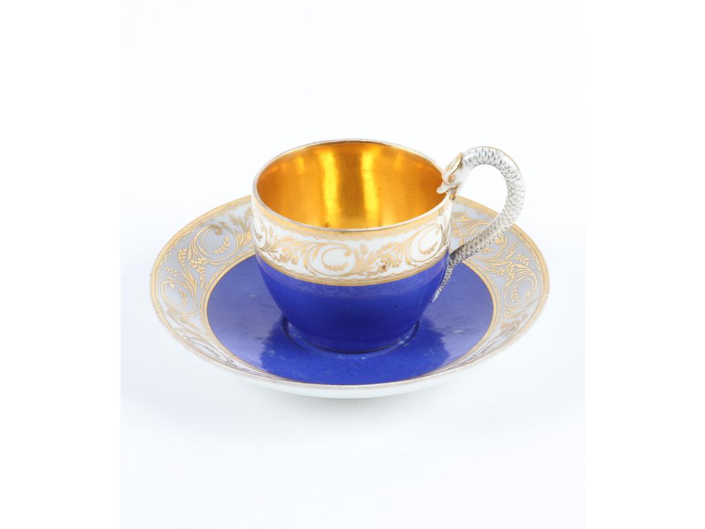 MEISSEN : Tasse et sous-tasse en porcelaine bleue et doré à décor de rinceaux. Poignée en forme de serpent. Marquée. (Bon état général, usures sur la sous-tasse).
