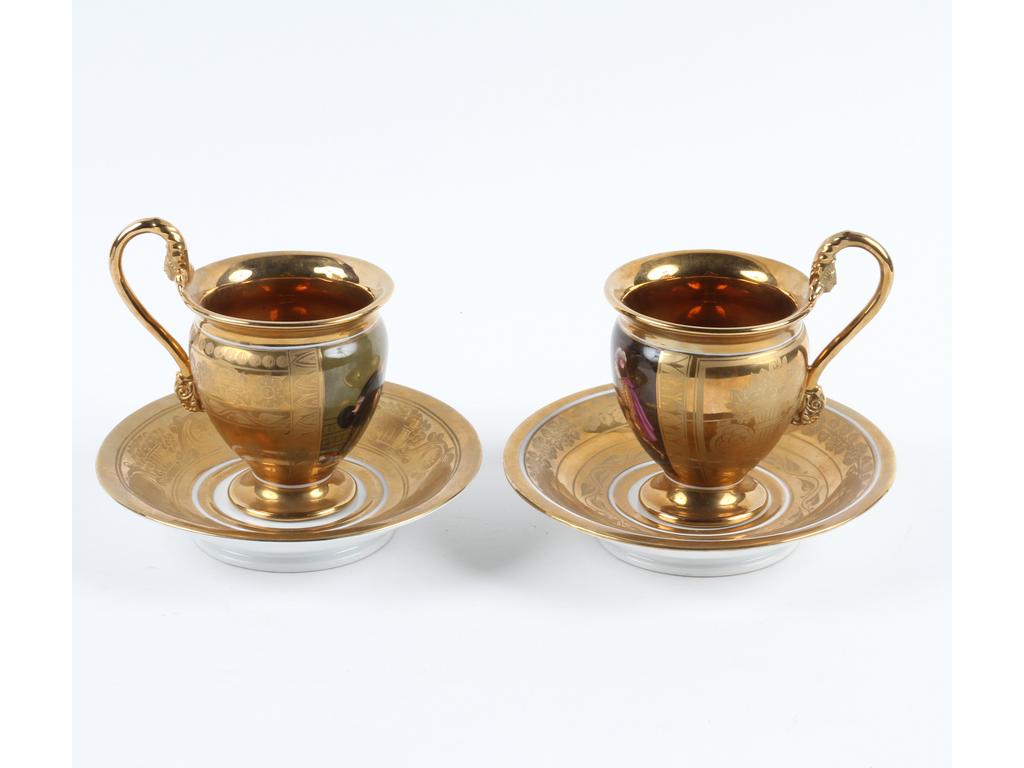 PARIS : Paire de tasses et sous-tasses en porcelaine entièrement dorée et à décor peint de deux scènes animées. Epoque Restauration. (Sous-tasses à décor différent). Bon état. Hauteur : 12 cm.