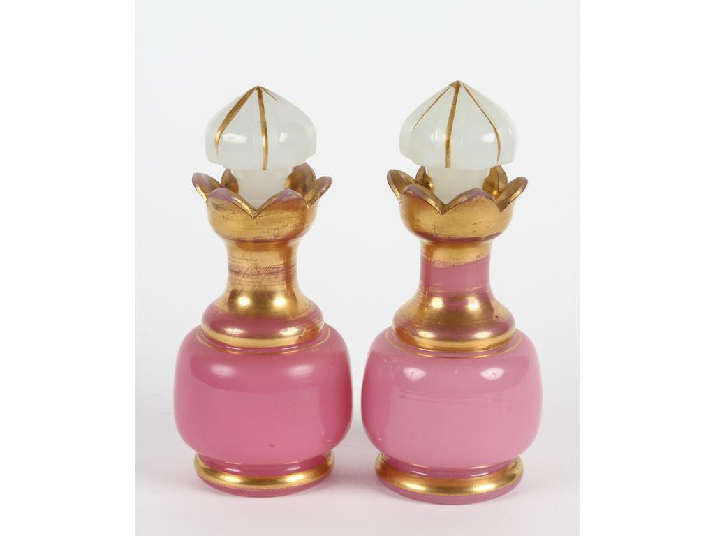 Paire de petits flacons en opaline rose à décor doré, bouchons en opaline blanche. Hauteur : 14 cm. (Usures à la dorure, infime éclat sur un des cols)