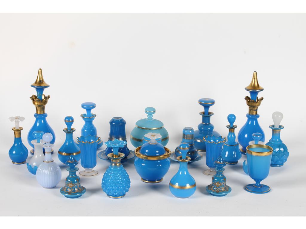 Ensemble de flacons, gobelets, sucriers et petits verres de nuit en opaline bleue et dorée. En tout 23 objets. (Quelques accidents dont le bouchon des plus grands flacons).