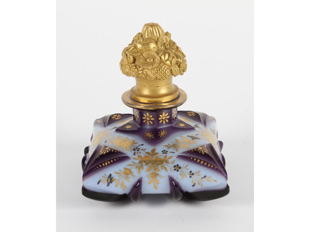 Joli flacon de forme coussin en opaline blanche et améthyste taillée orné d'un décor peint et doré de petites fleurs. Le bouchon en verre et bronze doré. (Les quatre angles avec éclats légers dont un plus important) Côtés : 9 x 9.5 cm. Hauteur : 12 cm.