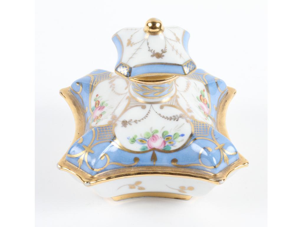 Flacon de forme hexagonale en porcelaine blanche peint de fleurs sur fond bleu et doré. Bon état. Côtés : 12 x 12 cm. Hauteur : 12 cm.