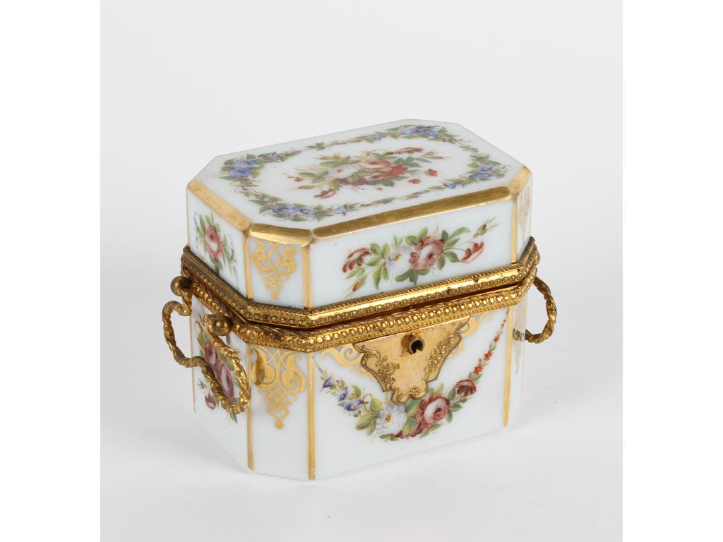 Coffret de forme octogonale en opaline blanche à décor peint de bouquets et guirlandes de fleurs, les arrêtes dorées. Sur une petite monture en laiton et tôle dorée. (Bon état, infimes usures de dorure et ouvert sans la clé). Dim : 9 x 10 x 7 cm.