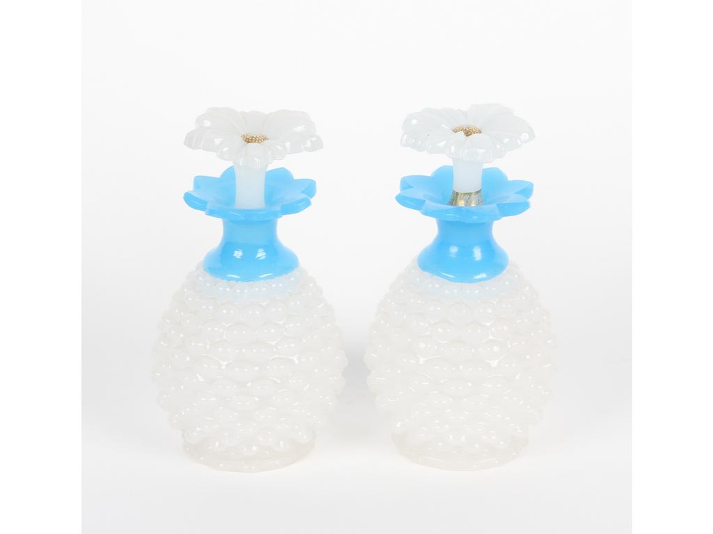 Paire de flacons en opaline blanche et bleue moulée à décor perlé. Les bouchons en forme de marguerites. Bon état. Hauteur : 17 cm.