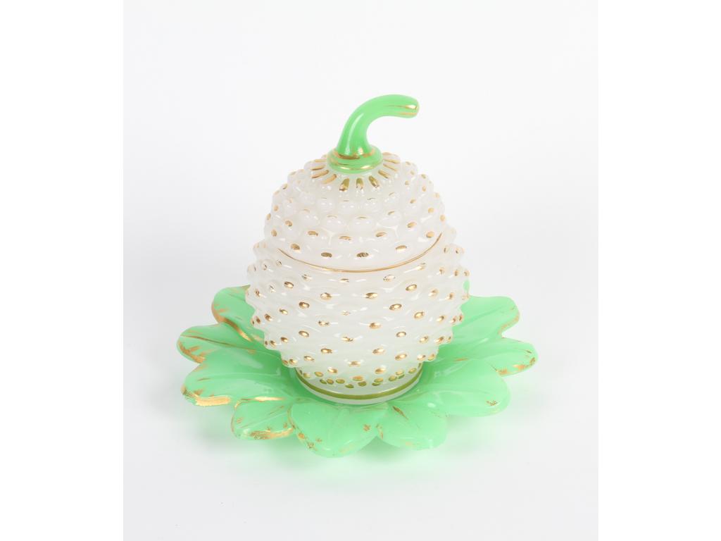 Boîte en opaline blanche moulée à décor perlé à l'imitation d'un fruit. Le fretel et la coupelle en opaline verte. L'ensemble rehaussé de dorure. (Usures à la dorure, petits éclats sur les rebords de la coupelle) Hauteur : 17 cm.