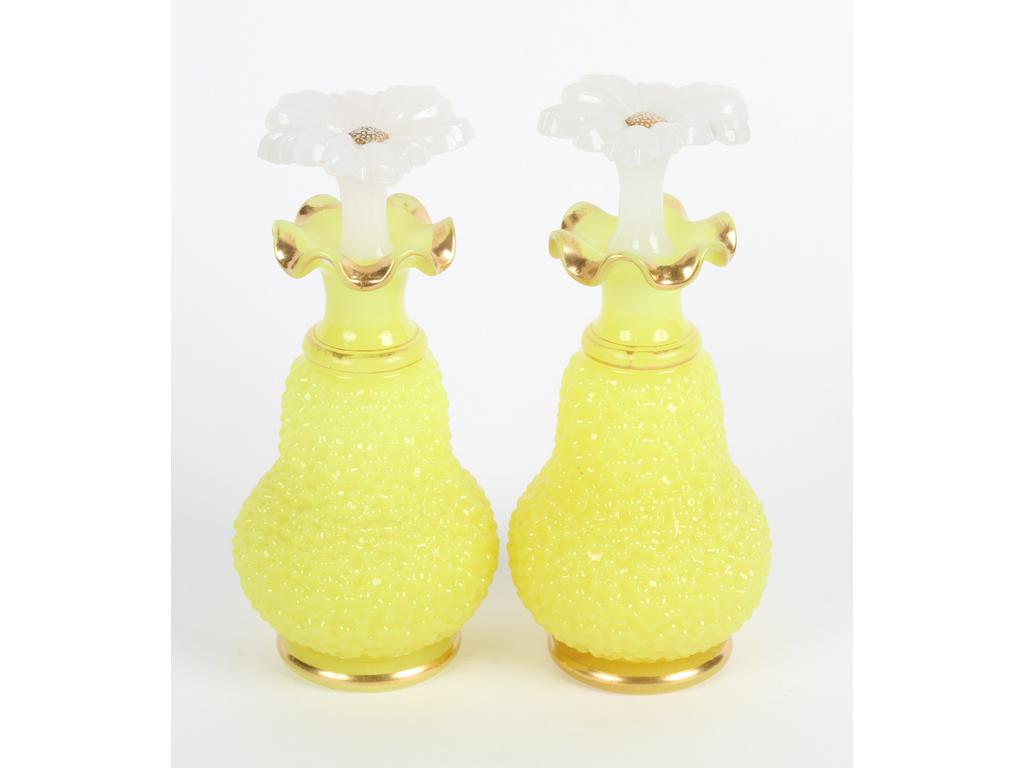 Paire de flacons en opaline jaune et blanche à décor granulé et rehauts dorés. (Bon état général, usures à la dorure). Les bouchons en forme de marguerites. Hauteur : 18 cm.