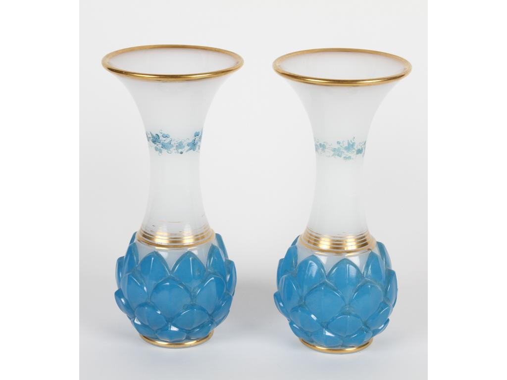 Paire de vases en opaline blanche et bleue moulée. La base à l'imitation d'une pomme de pin, le col peint de fleurs avec liserés dorés. (Petites usures à la dorure). Hauteur : 22 cm.