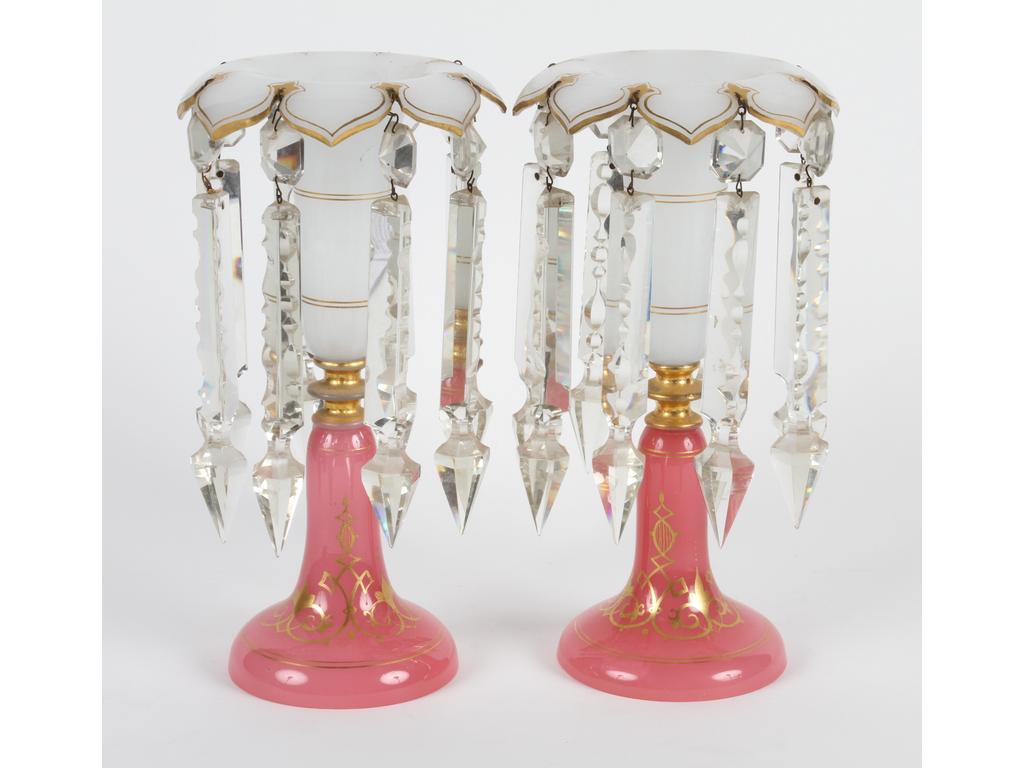 Paire de flambeaux en opaline blanche et rose en forme de corolles réhaussés de dorure. Les cols ornés de grandes pampilles en cristal taillé. Hauteur : 26 cm. ( à signaler deux infimes éclats sur un col et deux autres sur une pampille)