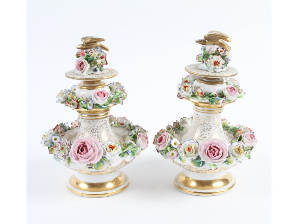 PARIS, Jacob PETIT : Paire de flacons à parfum en porcelaine blanche et dorée, ornés chacun de deux couronnes de fleurs en relief. Les bouchons ornés d'un oiseau. Marqués JP (Bouchons restaurés et quelques accidents aux fleurs). Hauteur : 20 cm.