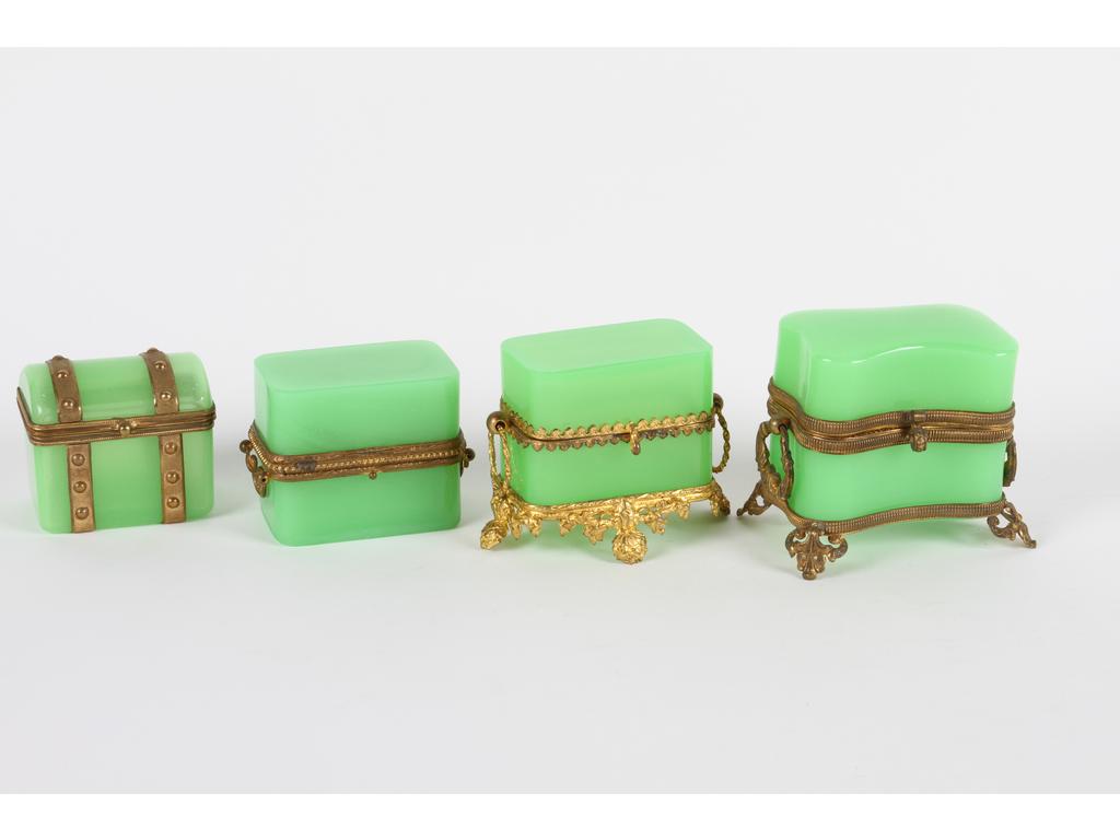 Ensemble de quatre coffrets en opaline verte dont un avec deux flacons senteur. Les quatre avec montures en laiton et tôle dorée. Bon état. Hauteurs de 6 à 8.5 cm.