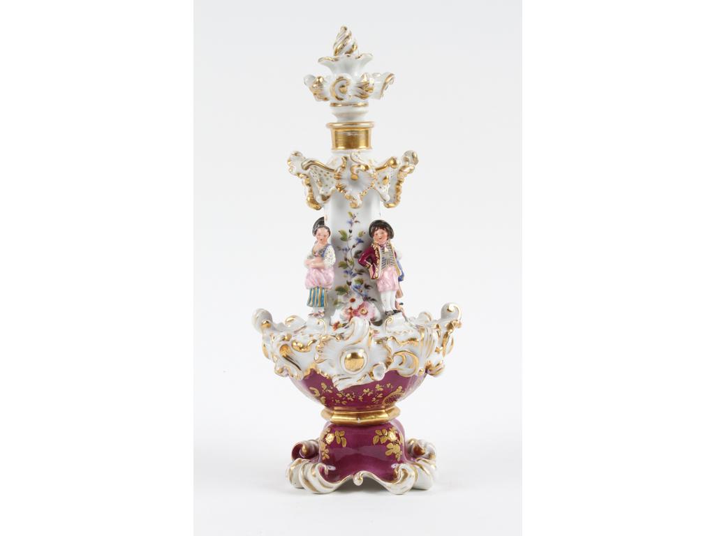 PARIS, Jacob PETIT : Joli flacon en porcelaine blanche à décor peint de fleurs, la base couleur lie de vin. Le col orné en relief de quatre petits personnages et l'ensemble rehaussé de dorure. Marqué J.P. Bon état. Hauteur : 27 cm.