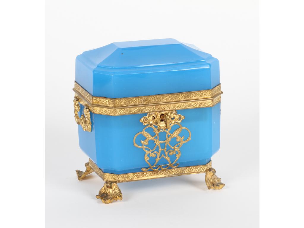Coffret à senteurs de forme octogonale en opaline bleue sur une monture en laiton et tôle dorée. A l'intérieur, deux flacons en cristal avec bouchons ornés de monuments parisiens en lithographie. (Bon état avec sa clé). Hauteur : 13 cm.