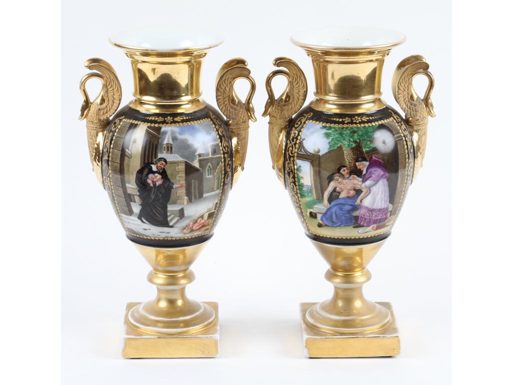 PARIS : Paire de vases balustres en porcelaine blanche entièrement dorés et peints de deux scènes de charité chrétienne et de bouquets de fleurs. Les anses en cols de cygnes. (Bon état général, usures à la dorure). Epoque Restauration. Hauteur : 33 cm.