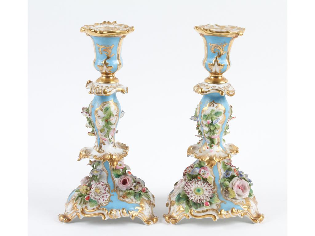 PARIS, Jacob PETIT : Paire de flambeaux en porcelaine blanche à décor peint bleu et doré, ornés en relief de fleurs. Marqués JP. (Bon état général, infimes éclats). Hauteur : 25 cm.