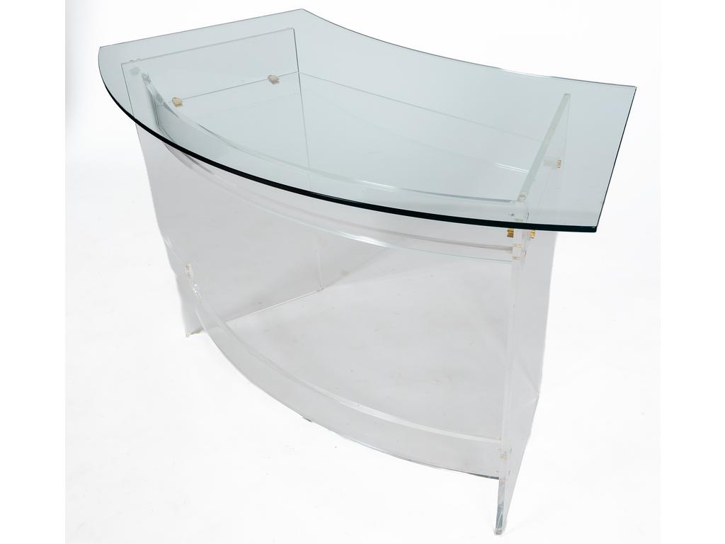 Petit bureau contemporain de forme arrondie. Plateau en verre reposant sur un piétement avec étagère et entretoise en plexiglass. Production David LANGE. Hauteur : 76 cm. Longueur plateau : 123 cm. Avec un fauteuil de bureau sur roulettes.