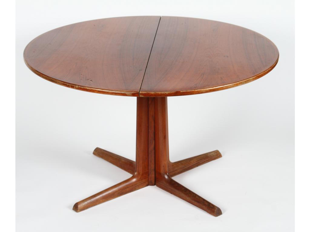 GUDME MOBELFABRIN, Editeur : Table de salle à manger en placage de palissandre, plateau circulaire reposant sur un piétement cruciforme. Avec ses deux allonges. Marque de l'éditeur au tampon sous le plateau. Travail Danois des années 60'. (Usures au vernis et quelques chocs). Hauteur : 72 cm. Diamètre : 121.5 cm.