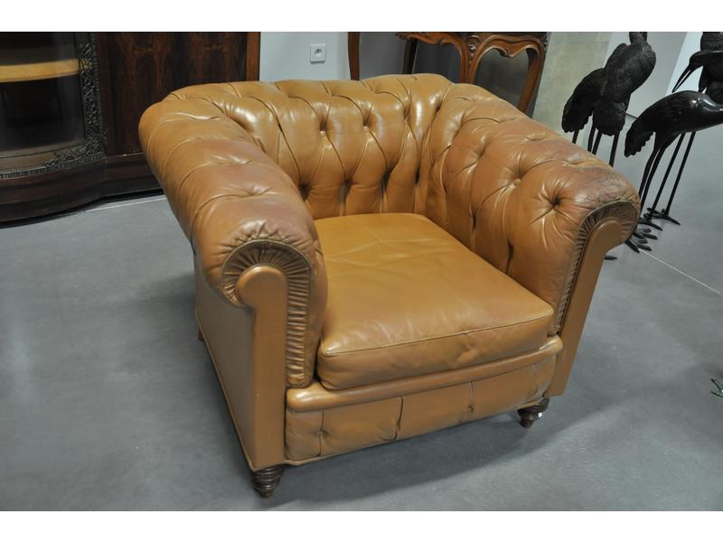Fauteuil chesterfield en cuir marron capitonné, pieds en bois. (