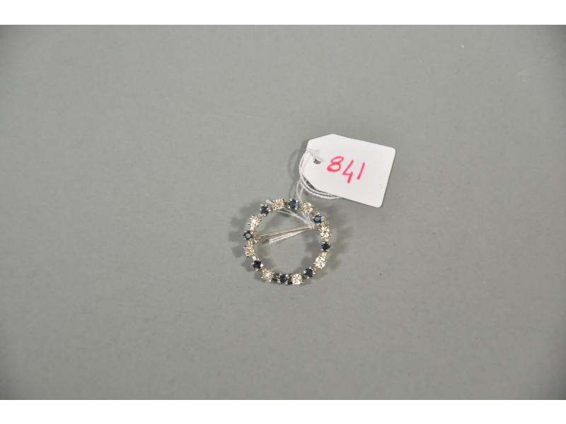 Une broche ronde en or gris ornée en alterné de petits diamants