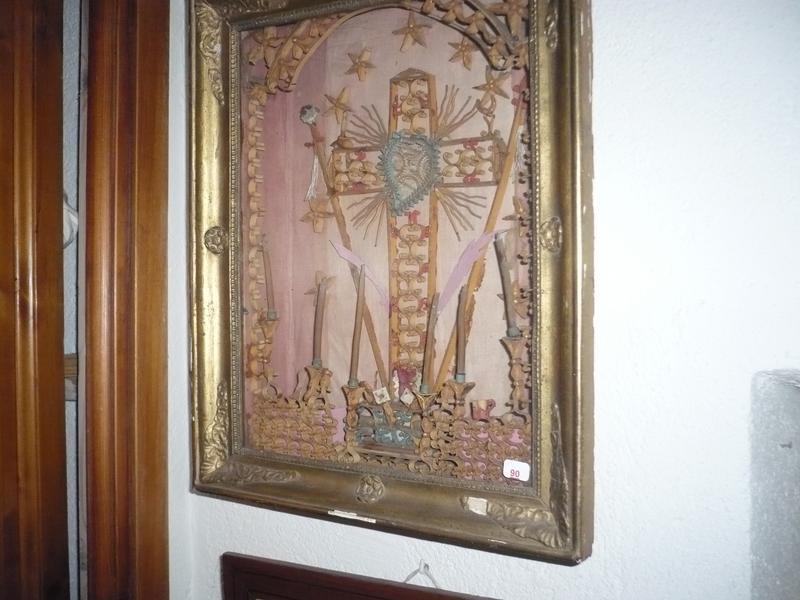 Un cadre reliquaire en forme de croix en paperolles dans un encadrement. Epoque Restauration. Dim. 41x33 cm.