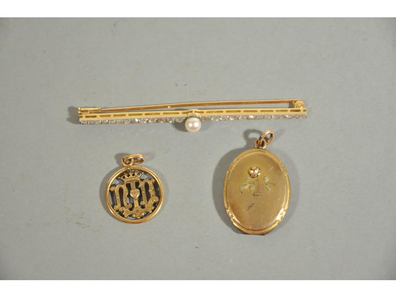 Broche-barrette en or et platine ornée en serti-clos d'une ligne de diamants taille ancienne en légère chute, en son centre d'une perle probablement fine (diam.: 5 mm).  Début XXe siècle.  Long.: 7 cm.  Poids brut : 5g10.  On y joint un médaillon et une médaille en plaqué or.
