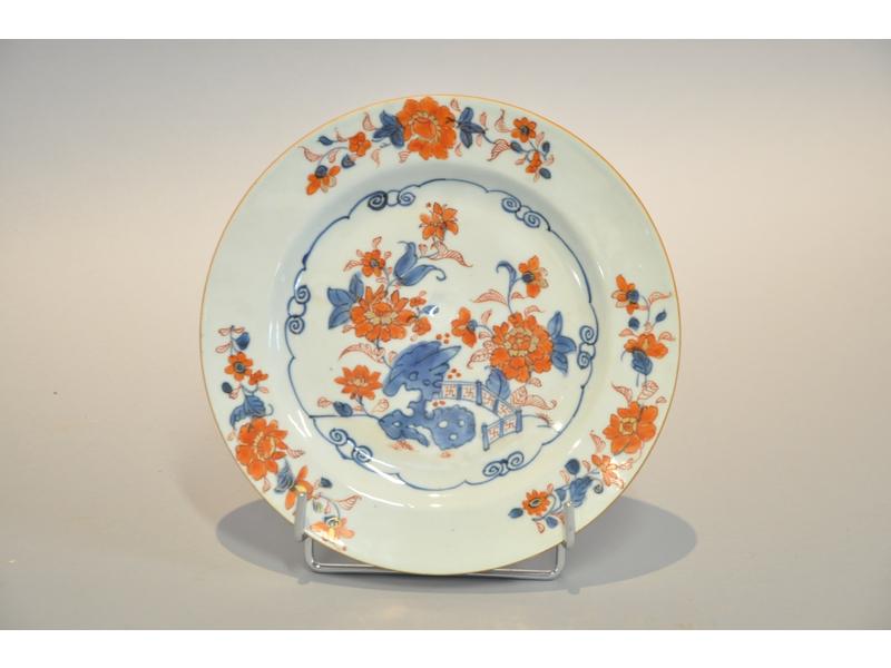 CHINE: Compagnie des Indes, assiette en procelaine blanche à décor peint polychrome et réhauts dorés de fleurs et barrière. Epoque XVIIIème. Diamètre: 23.5cm