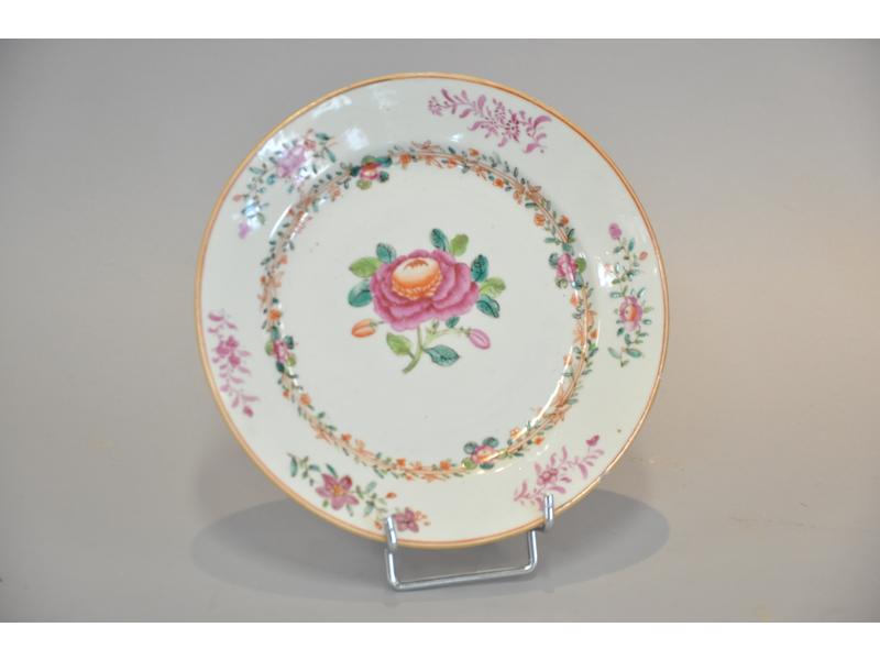 CHINE - Compagnie des Indes : Assiette en porcelaine blanche à décor polychrome et réhaut doré d'une rose au centre et de brindilles et petits bouquets sur le marli et aile.  Epoque XVIIIe siècle.  Diam.: 22.5 cm. (infime fêle)