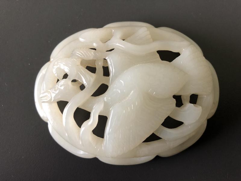 CHINE - XIXe siècle, dans le style Ming : Ornement de forme ovale en néphrite blanche à décor sculpté et ajouré de deux oiseaux. Long.: 8 cm. Expert : Cabinet Portier.