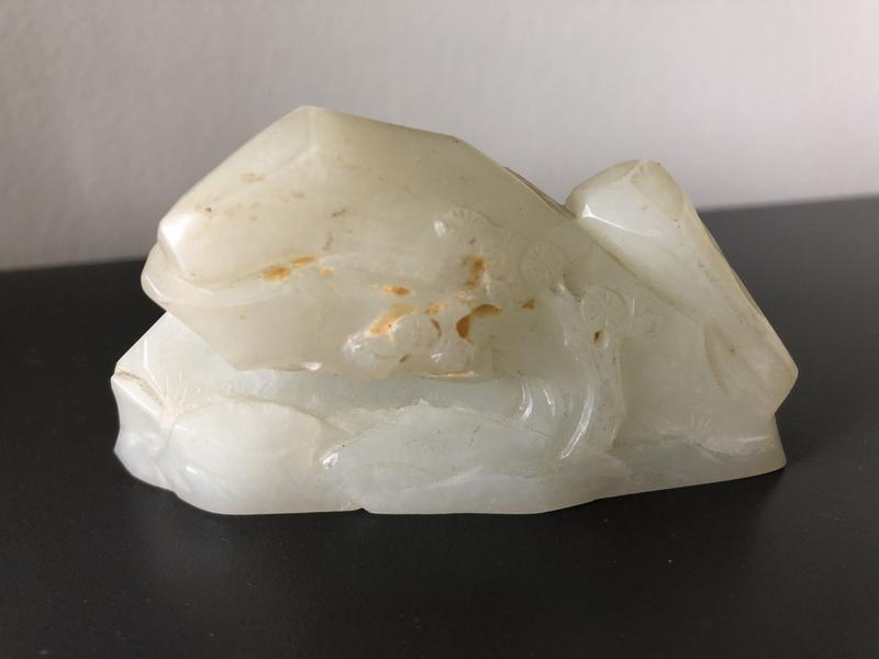 CHINE - XVIIIe/XIXe siècle : Petit rocher en néphrite céladon, à décor sculpté sur la face d'un pin. Dim. 4 x 7,5 cm. Expert : Cabinet Portier.