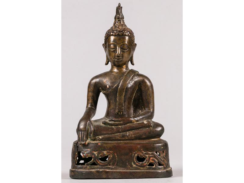 THAILANDE, Ayutthaya - XVIIe/XVIIIe siècle : Statuette de bouddha en bronze à patine brune, assis en padmasana sur un socle ajouré de fleurs, les mains en bhumisparsa mudra (geste de la prise de la terre à témoin). (fente). Hauteur : 18.5 cm