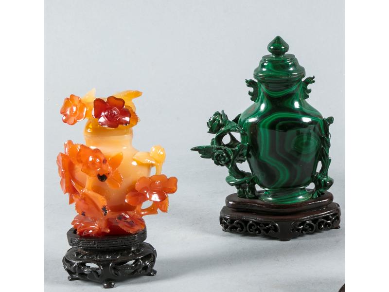 Lot de deux petits vases couverts : l'un en pierre dure sculptée à décor floral, hauteur : 10.5 cm.  L'autre en malachite sculptée, hauteur : 11.5 cm.   Sur socles en bois.  Travail Extrême-Orient.  XXe siècle.