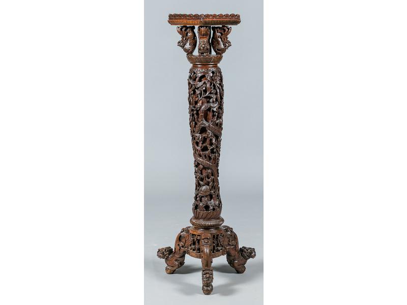 Personnage extrême oriental, à ses pieds un petit dragon (fentes, manque une partie de la laisse). Hauteur : 45 cm.  Il repose sur une selette en bois exotique à riche décor sculpté et ajouré de fleurs et serpents. Le plateau carré (23x23 cm) repose sur quatre petits dragons. Début XXe siècle. Haute