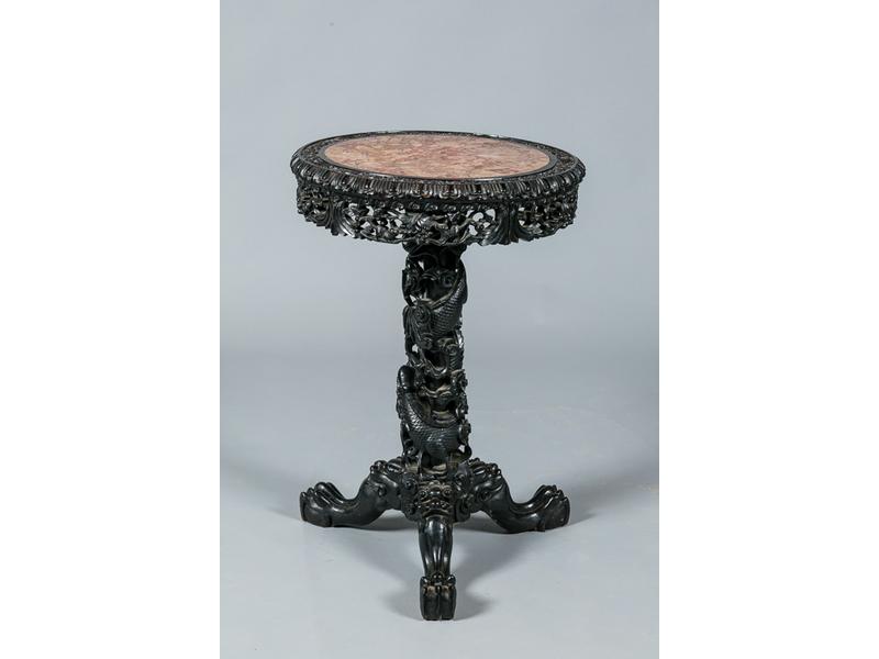 Guéridon en bois exotique noir richement sculpté et ajouré. Plateau en marbre rouge veiné reposant sur un fût orné d'un dragon et trois pieds griffes. Vers 1900. Travail extrême oriental. Hauteur : 83 cm, diamètre : 55 cm.