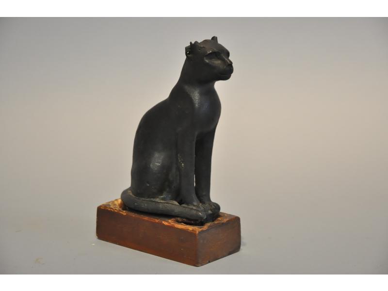 Chat Bastet en bronze à patine noire. Travail de style Saïte. Hauteur : 14 cm.  Sur socle en bois. (oreilles cassées)