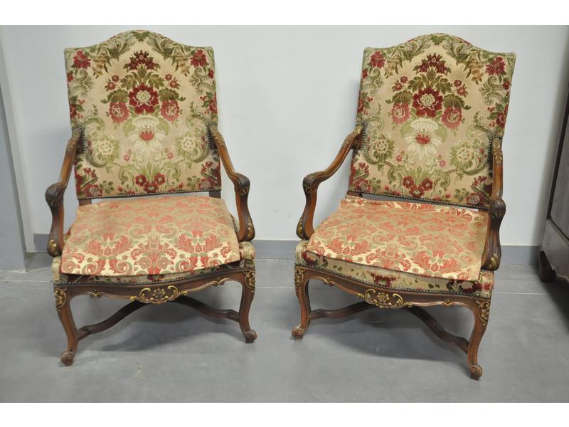 Paire de fauteuils de style Régence à dossier plat en noyer naturel mouluré et sculpté de feuilles d'acanthe et rinceaux rehaussés.  Il reposent sur un piètement cambré à entretoise.  XIXe siècle.