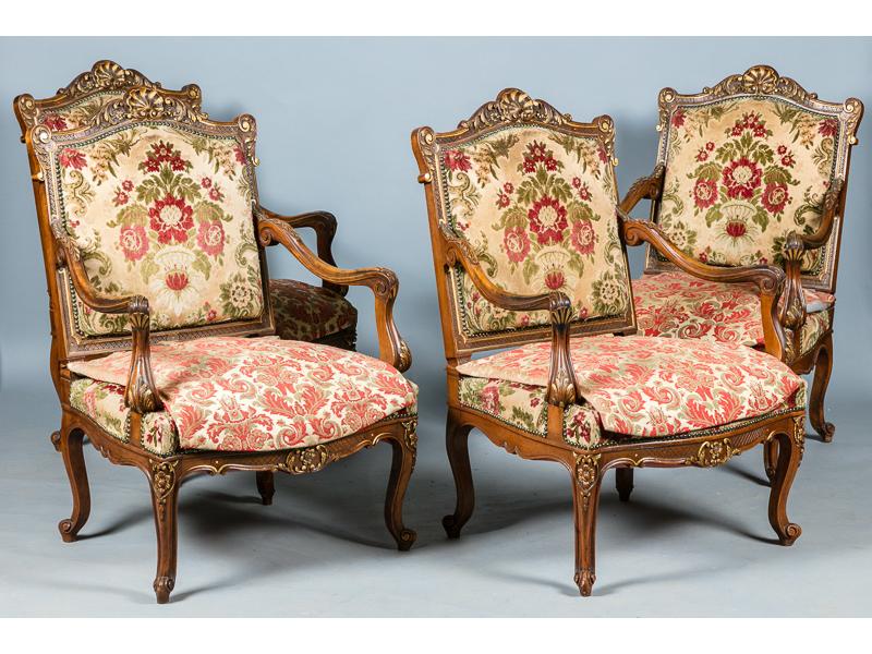 Mobilier de salon de style Régence en noyer naturel mouluré et sculpté et rehauts dorés à décor d'une coquille, rinceaux et feuilles d'acanthe.  Il comprend un canapé et quatre fauteuils à dossier plat.  XIXe siècle.