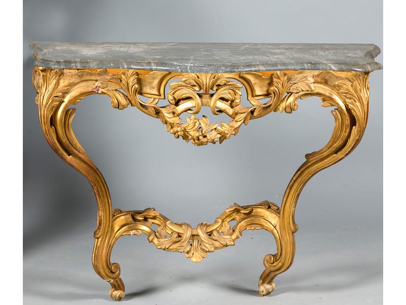 Console d'époque Louis XV à toutes faces galbées en bois sculpté, ajouré et doré (redoré) de feuillages, guirlandes de fleurs. Plateau de marbre gris reposant sur deux pieds en console reliés par une entretoise feuillagée (console fragilisée, bouts de pied accidentés, ceintures renforcées aux angles