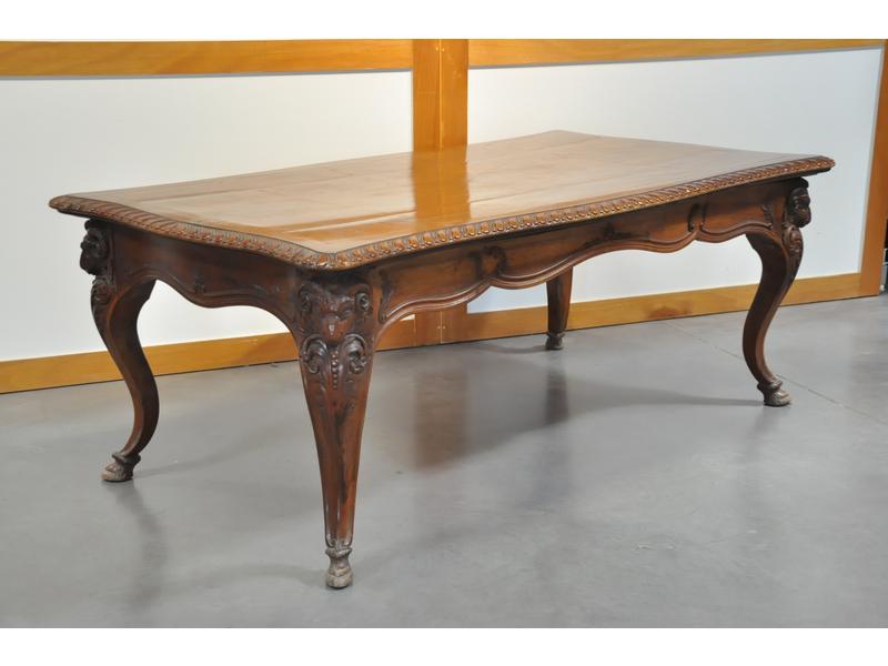 Importante table en noyer et placage de noyer de forme rectangulaire, plateau à décor de godrons reposant sur un piètement de forme jarret surmonté d'une tête de bélier sculptée réuni par une traverse mouvementée.  Fin XIXe siècle.  Dim.: 76x200x108 cm. (plateau probablement rapporté, non d'origine)