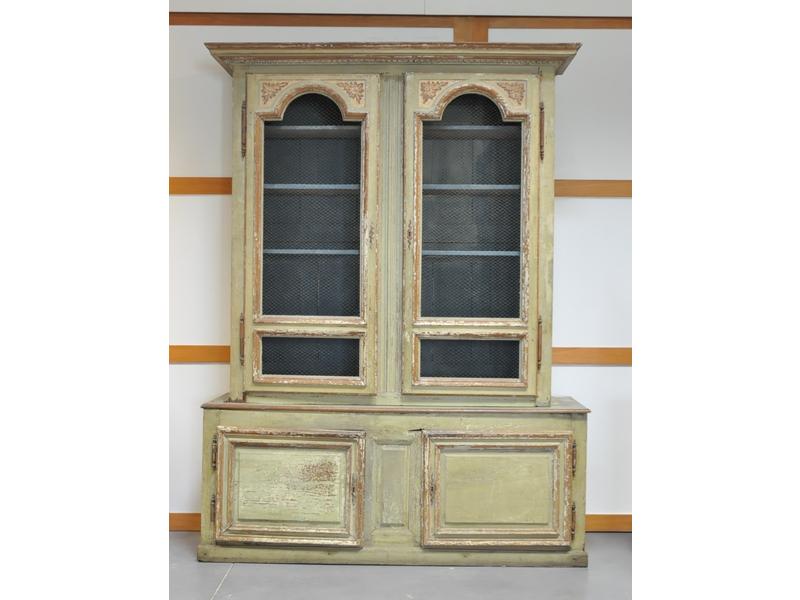 Bibliothèque en bois laqué vert rechampi à léger retrait ouvrant par deux portes moulurées à décor sculpté et grillagées en partie supérieure et deux vantaux en partie basse.  Ancien travail de style Régence.  Dim.: 268x199x59 cm.