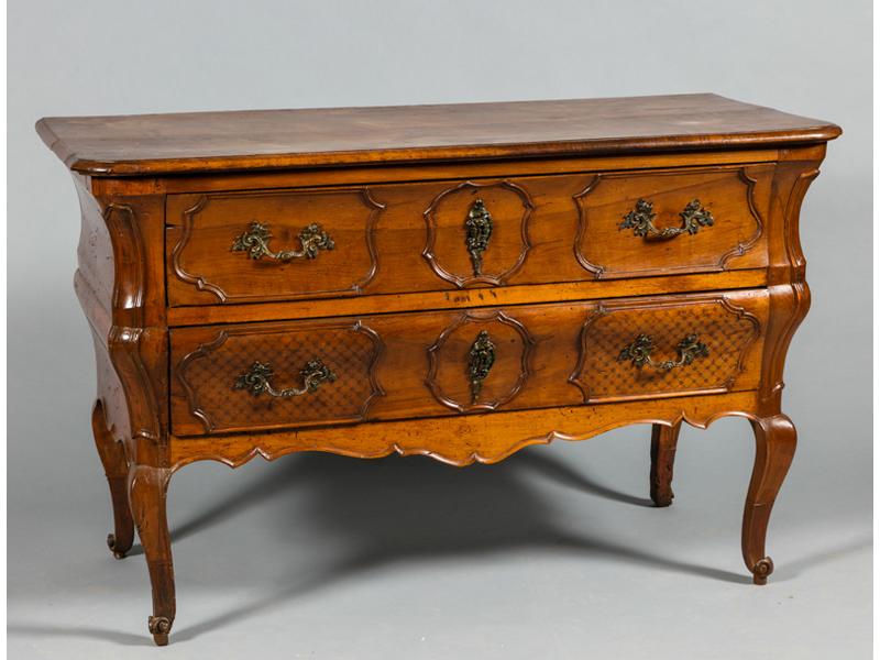 Commode Castraise en noyer.  Façade et côtés mouvementés.  Elle ouvre par deux larges tiroirs à décor mouluré et ciselé de treillages.  Elle repose sur quatre pieds cambrés (les quatre entés).  Epoque XVIIIe siècle.  Poignées et entrées de serrures en bronze (rapportées).  Dim.: 83x131x63 cm.