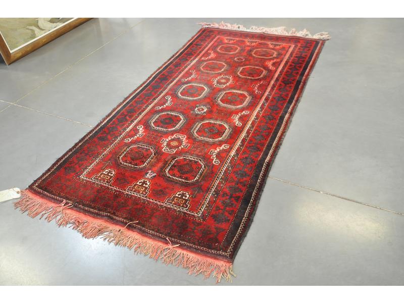 IRAN : Tapis en laine à décor de dix petits médaillons sur fond bordeaux. Dim : 223 x 109 cm (franges teintées)
