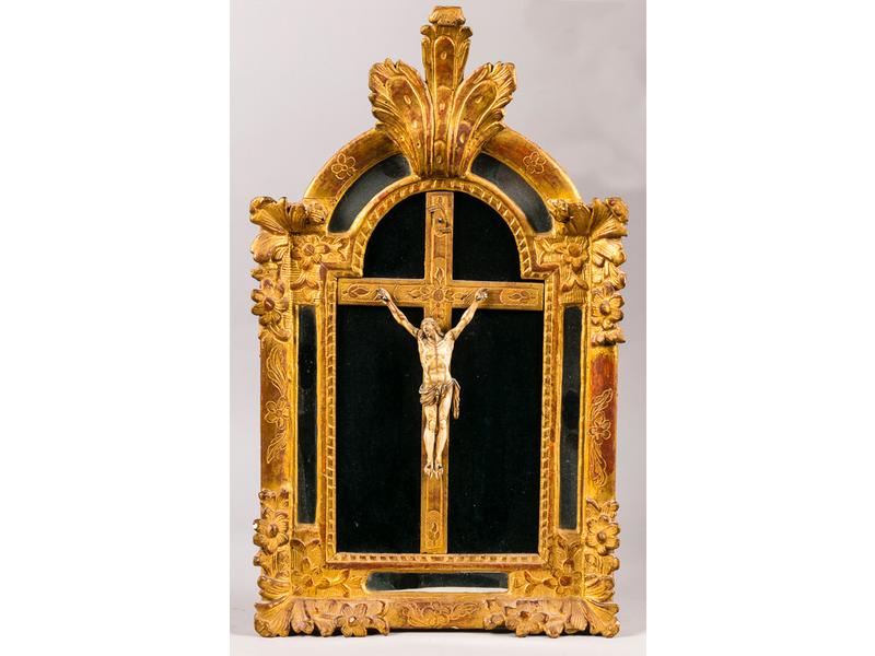 Christ en ivoire sculpté dans un encadrement à parecloses en bois sculpté et en partie redoré à décor floral surmonté d'un large feuillage d'acanthe. Epoque XVIIIe siècle. Dim: 67x40 cm.