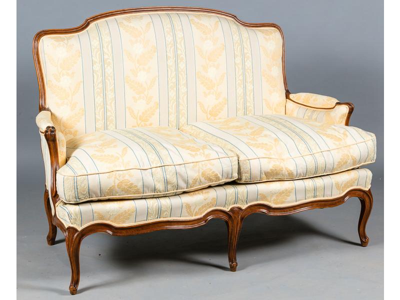 Canapé de style Louis XV (deux places) en bois naturel mouluré.  Traverse à double évolution reposant sur cinq pieds.  Garniture en tissu en bon état.