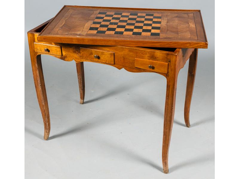 Table à jeux tric-trac d'époque Louis XV en noyer.  Plateau rectangulaire marqueté sur une face d'un damier et feutré sur l'autre face, découvrant un intérieur également marqueté.  Elle ouvre par deux tiroirs latéraux et repose sur quatre pieds cambrés.  Dim.: 73.5x81x53 cm. (quelques trous de vers)