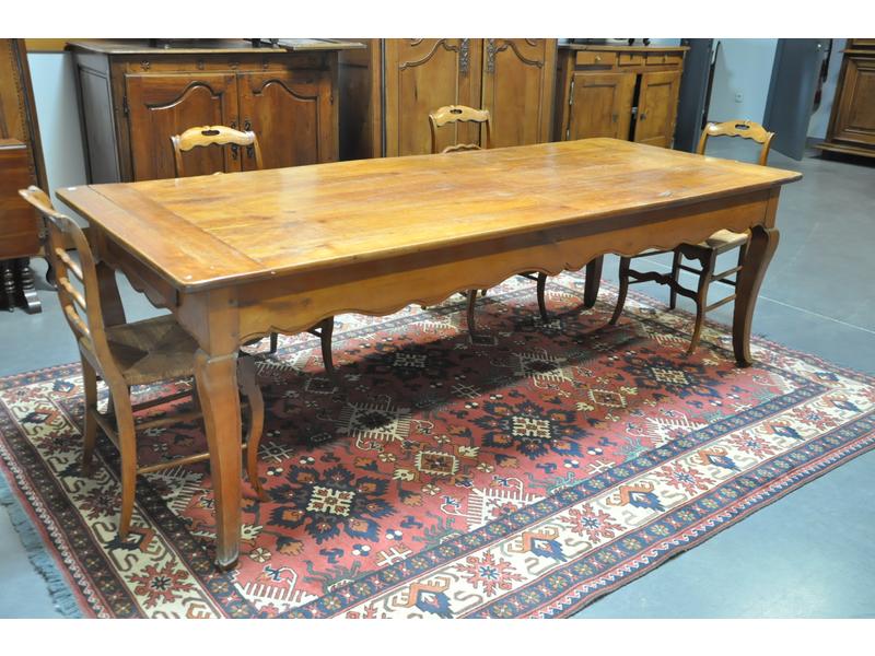 Grande table rectangulaire de style Louis XV en merisier reposant sur un piètement cambré relié par une ceinture mouvementée ouvrant par un tiroir et une allonge rapportés.  XIXe siècle.  Dim.: 76x93x226 cm. (fentes)