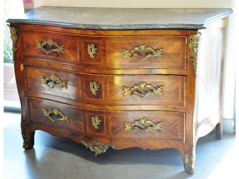 Belle commode d'époque Louis XV galbée toutes faces en marqueterie de bois de rose et bois précieux ouvrant par trois tiroirs ornés de filets de bois clair.  Belle ornementation de rbonze telle que espagnolettes à tête d'indien, poignées, entrées de serrures et sabots.  Plateau de marbre gris.  Dim.